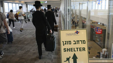  A sign points towards the nearest bomb shelter as passengers disembark from a commercial flight on October 11, 2023 in Tel Aviv, Israel.