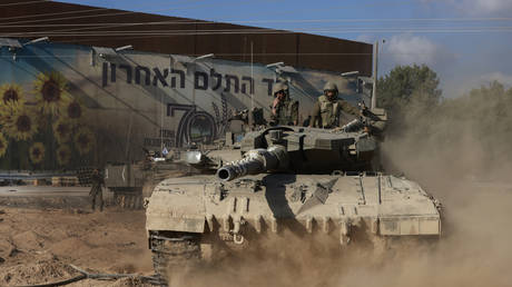 Israeli troops manuever a tank near kibbutz Nahal Oz on the border with the Gaza Strip on October 15, 2023