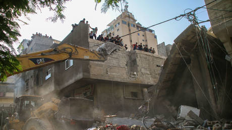 KHAN YUNIS, GAZA - OCTOBER 22: Palestinian rescuers and civilians search for survivors in ruins of buildings destroyed by Israeli air raids