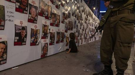 FILE PHOTO: A young boy paints on a wall next to photos of Israelis missing and held captive by Hamas militants, October 21, 2023