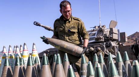 An Israeli army soldier carries a 155mm artillery shell near a self-propelled howitzer deployed at a position near the border with Lebanon in northern Israel, October 18, 2023