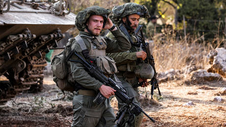 Israeli army soldiers stand by a tracked vehicle at a position in the upper Galilee region of northern Israel on October 28, 2023.