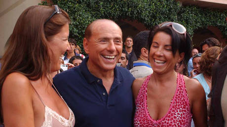FILE PHOTO: Silvio Berlusconi is photographed with two unidentified women as he goes for a walk in Porto Rotondo, Sardinia, August 19, 2004