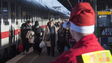 Asylum-seekers seen walking along a platform after getting off a train at the Schoenefeld station near Berlin, Germany.