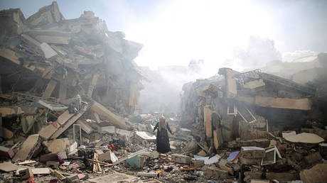 A resident gets upset as she walks amid near the rubble of residential buildings after Israeli airstrikes at al-Zahra neighborhood in Gaza Strip on October 19, 2023.