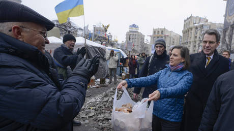U.S. Assistant Secretary for European and Eurasian Affairs Victoria Nuland offers food to pro-European Union activists as she and U.S. Ambassador to Ukraine Geoffrey Pyatt, right, walk through Independence Square in Kiev, Ukraine, Wednesday, Dec. 11, 2013.