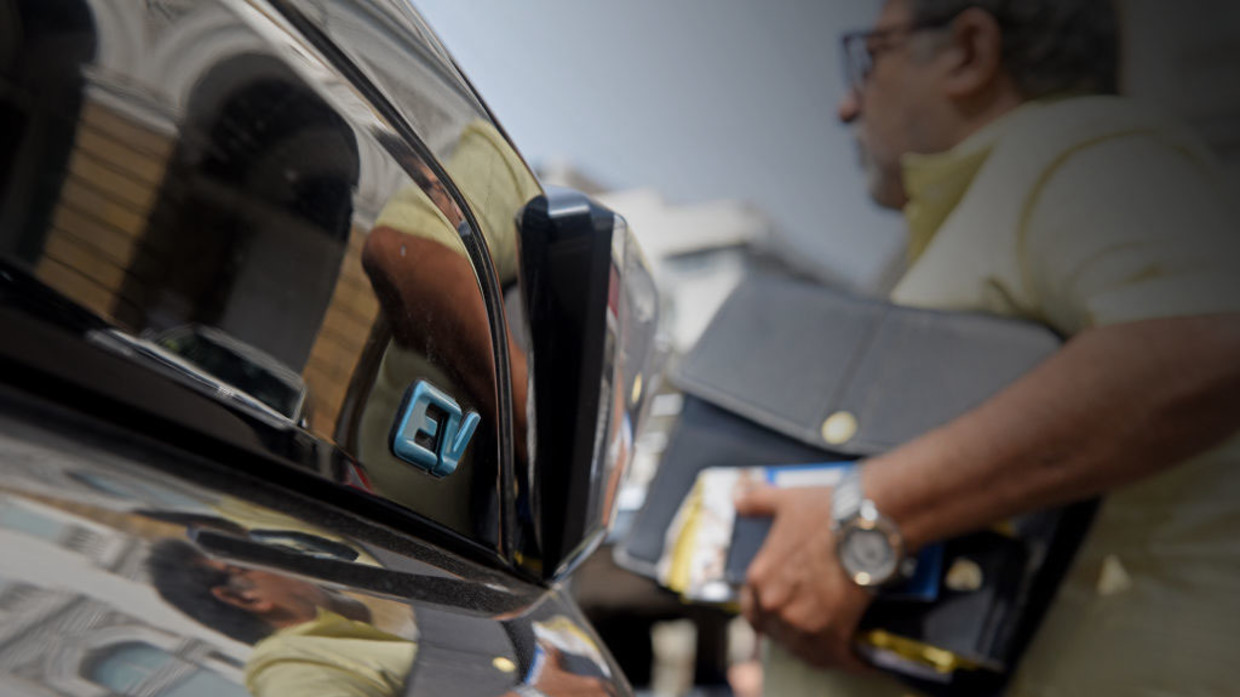 FILE PHOTO: A man walks past an EV (Electric Vehicle) car in Mumbai, India, on January 31, 2023.