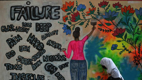  A college student walks past a graffiti on World Mental Health Day in Srinagar.