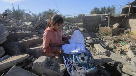 A Palestinian girl searches through her school bag in the rubble of her destroyed home on Saturday in Rafah, Gaza.
