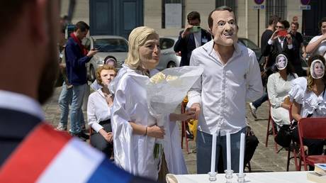 FILE PHOTO: French activists posing as President Emmanuel Macron and Marine Le Pen perform a fake wedding to denounce government policy, in 2022.