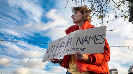 A lone Jewish woman holds a placard saying "Not in our names, Jew for a free Palestine" at a pro-Palestinian demonstration calling for an end to Israeli attacks on Gaza.