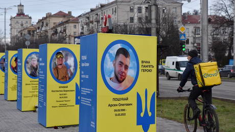 FILE PHOTO: A man from delivery service rides a bicycle past stands of portraits of fallen Ukrainian soldiers