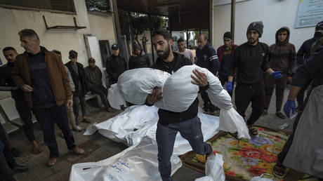 A Palestinian man carries the body of his relative killed in the Israeli bombardment of the Gaza Strip, outside a morgue in Rafah, Gaza, December 29, 2023
