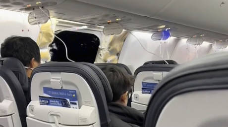 This image from video provided by Elizabeth Le shows passengers near the damage on an Alaska Airlines Boeing 737 Max 9, Flight 1282, which was forced to return to Portland International Airport on Friday, January 5, 2024.