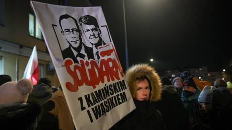 A protester holds a sign with effigies of detained former MPs Mariusz Kaminski and Maciej Wasik