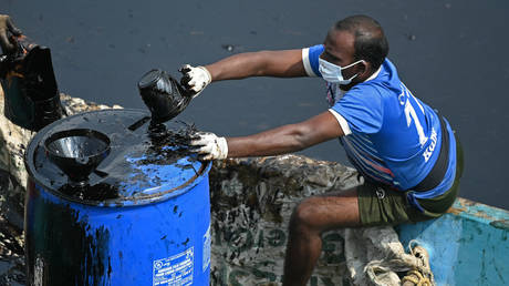 FILE PHOTO: A worker collects oil after it spilled over the backwater at Ennore creek in the aftermath of Cyclone Michaung, on the outskirts of Chennai on December 13, 2023.