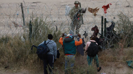 Immigrants near Juarez, Mexico, try to cross into the US last month through concertina wire strung by Texas National Guard troops.