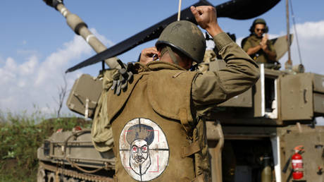 An Israeli soldier wearing a patch on the back of his flack jacket showing Hezbollah leader Hassan Nasrallah as a target, in northern Israel, as an artillery unit shells southern Lebanon on January 4, 2024