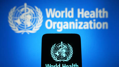 In this photo illustration, the World Health Organization (WHO) logo is seen on a smartphone and in the background