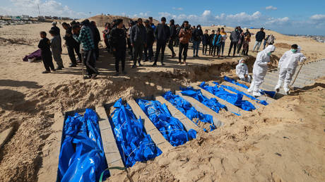 Gaza-based Palestinian Health Ministry workers bury the bodies of unidentified Palestinians after they were returned by Israel, at a mass grave east of Rafah in the southern Gaza Strip on January 30, 2024
