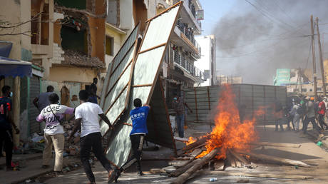 Protesters barricade a street by burning wood, tires and using iron panels as they gather at the Nation Square to stage protest against postponement of presidential election in Dakar, Senagal on February 09, 2024.