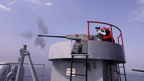 FILE PHOTO: A sailor firing atop an Iranian warship during navy drills.