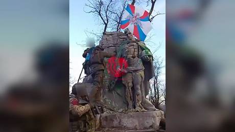 A screenshot from a video purportedly showing Russian soldiers placing a flag on a monument to Soviet soldiers in Avdeevka.