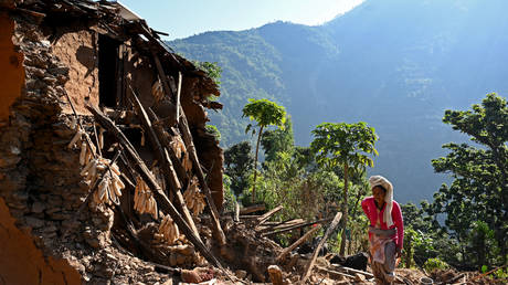 A survivor of a recent earthquake, walks over the ruins of a house, in Chiuri village at Jajarkot district on November 5, 2023. At least 157 people were killed in isolated western districts of the Himalayan country when the 5.6-magnitude earthquake hit late November 3.