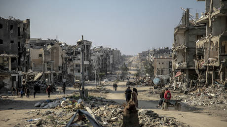 Palestinians walk past buildings destroyed during Israeli strikes in Beit Lahia in northern Gaza, on February 26, 2024, amid continuing battles between Israel and the Palestinian militant group Hamas.