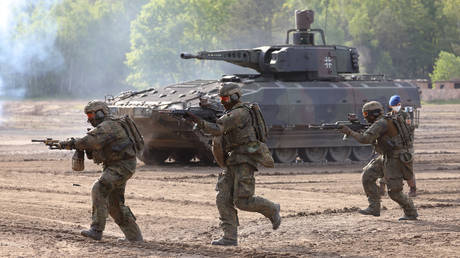 FILE PHOTO: Bundeswehr soldiers run past a Puma mechanized infantry combat vehicle.