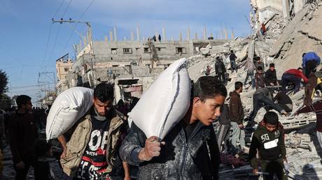 Palestinians walk past buildings destroyed by Israeli airstrikes in Rafah, Gaza, on March 9, 2023.