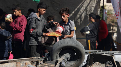 Palestinian children collect food at a donation point provided by a charity group in the southern Gaza Strip city of Rafah, on November 30, 2023