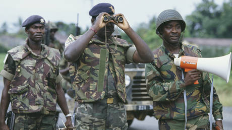 FILE PHOTO. ECOMOG soldiers on patrol look down a road in Monrovia.