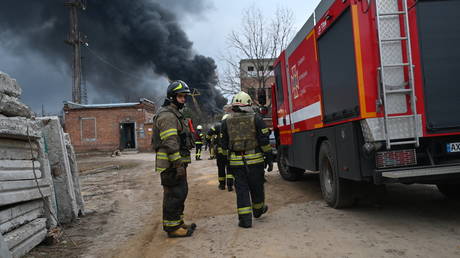 Firefighters stand near a fire at an electrical substation after a missile attack in Kharkiv, on March 22, 2024.