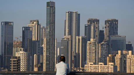 A man looks towards high rise buildings in Mumbai. High-rise buildings dominate the construction landscape, constituting approximately 77% of the Mumbai skyline.