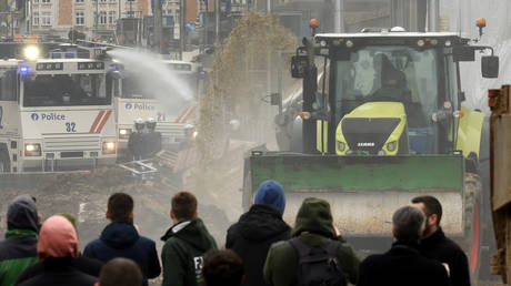 Police use a water canon on a farmer in a tractor spraying hay and manure, March 26, 2024.