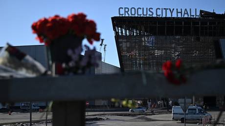 Flowers and toys are placed on the roadside in front of the burned-out Crocus City Hall in Moscow Region following a terrorist attack, March 27, 2024.