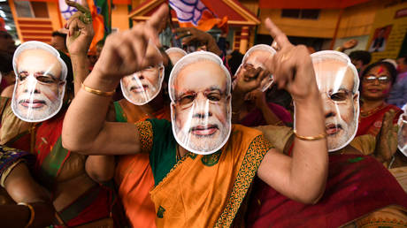 Indian Bharatiya Janata Party (BJP) supporters wearing masks of Indian Prime Minister Narendra Modi dance as they celebrate on the vote results day for India's general election at BJP office in Guwahati on May 23, 2019.