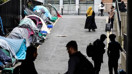 People walk past tents at a makeshift refugee camp outside the Irish government's International Protection Office in Dublin, Ireland, June 12, 2023