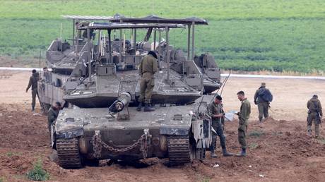 FILE PHOTO: Israeli army troops stand around their tank in an area along the border with the Gaza Strip.