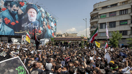 Iranians follow a truck carrying coffins of the late President Ebrahim Raisi and his companions, who were killed in a helicopter crash, during a funeral ceremony for them on May 22, 2024 in Tehran, Iran.
