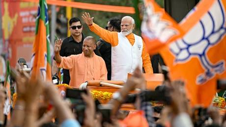 Narendra Modi (R), India's Prime Minister and leader of the ruling Bharatiya Janata Party (BJP) with Yogi Adityanath (2L), Chief Minister of the country's Uttar Pradesh state waves to the crowd during his roadshow on the eve of filing of his election nomination papers, in Varanasi on May 13, 2024.