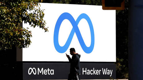 FILE PHOTO: A pedestrian walks in front of a new logo and the name 'Meta' on the sign in front of Facebook headquarters.