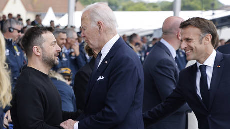 US President Joe Biden (C) shakes hands with Vladimir Zelensky (L) as France's President Emmanuel Macron (R) looks on in Saint-Laurent-sur-Mer, in northwestern France, on June 6, 2024