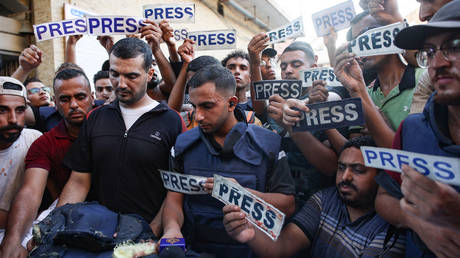 Mourners and colleagues holding ‘press’ signs surround the body of Al-Jazeera Arabic journalist Ismail al-Ghoul, killed along with his cameraman Rami al-Refee in an Israeli strike during their coverage of Gaza’s Al-Shati refugee camp, on July 31, 2024.