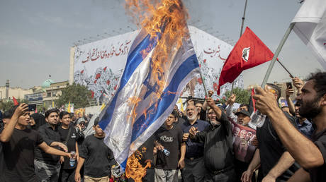 FILE PHOTO. Iranians burn a representation of the Israeli flag during funeral ceremony for assassinated Hamas leader Ismail Haniyeh in Tehran