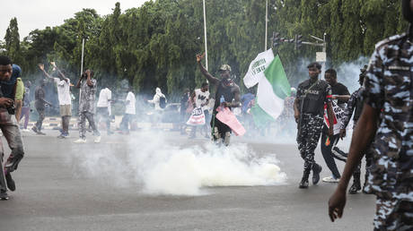 Demonstrators react as Nigerian policemen fire tear gas canisters during the End Bad Governance protest in Abuja on August 1, 2024.