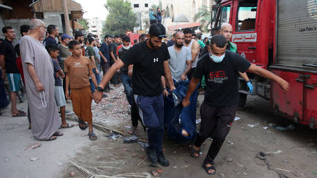 People remove the corpse of a person killed in an Israeli strike on a school in Gaza City.