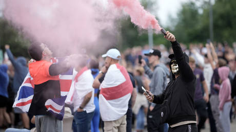 Anti-migration protesters holds a flare demonstrate outside a hotel housing asylum seekers in Rotherham, England, August 4, 2024