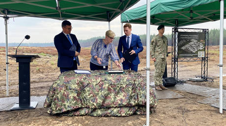 Lithuania's Minister of Defense Laurynas Kasciunas (l) and Lithuania's Prime Minister Ingrida Simonyte (2nd from left) take part in a ceremony at which a time capsule is buried at the future site of a German Bundeswehr brigade.